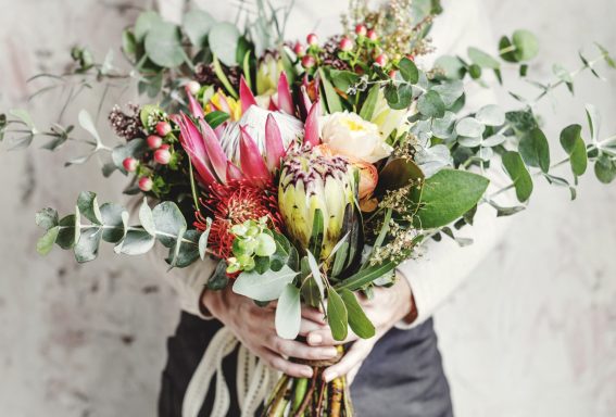 Bunte Blumenstrauß mit Eukalyptus und verschiedenen Blüten in Händen gehalten.